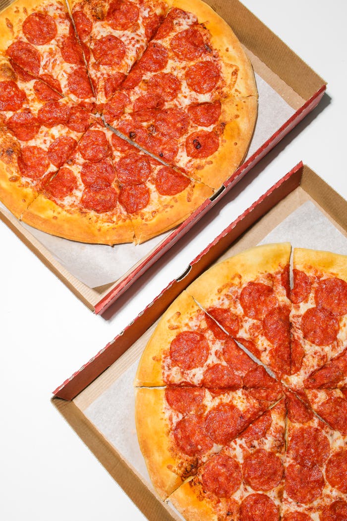 Two freshly baked pepperoni pizzas in open cardboard boxes, ready to enjoy.